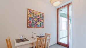 A dining area with a table set for two, a colorful floral artwork above the table, and a sliding glass door leading to an outdoor area. - GuestHost - Cozy apartment of about 80 sqm, able to accommodate up to 5 people, located on the fourth floor of a building with a lift.The property is located in a residential neighborhood of Turin, in an area full of all comforts and well connected to th (Turin)