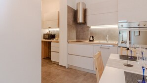 A modern kitchen with a built-in oven, a coffee maker, and a kettle on the counter. - GuestHost - Cozy apartment of about 80 sqm, able to accommodate up to 5 people, located on the fourth floor of a building with a lift.The property is located in a residential neighborhood of Turin, in an area full of all comforts and well connected to th (Turin)