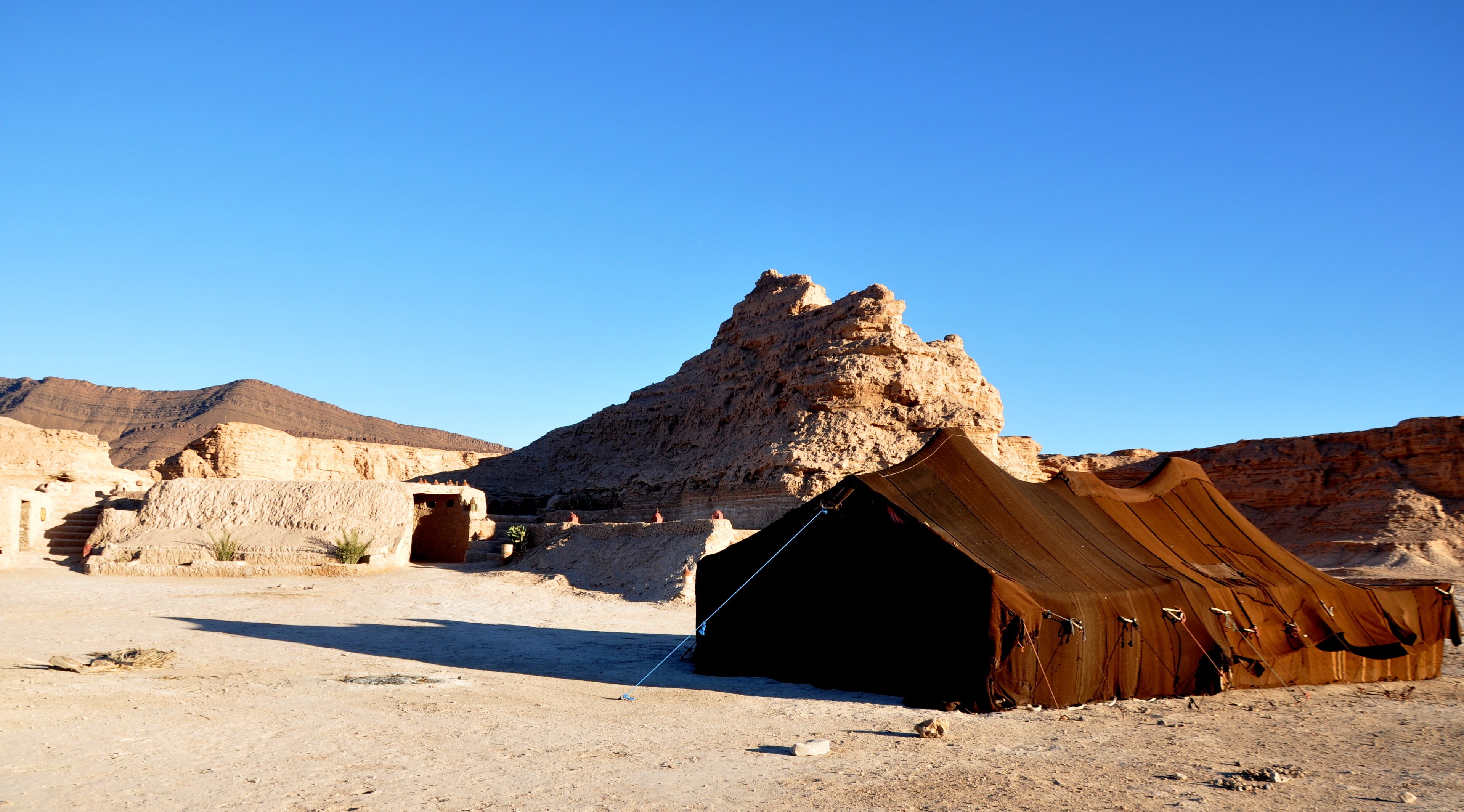 A desert landscape with a tent-like structure and ancient ruins.