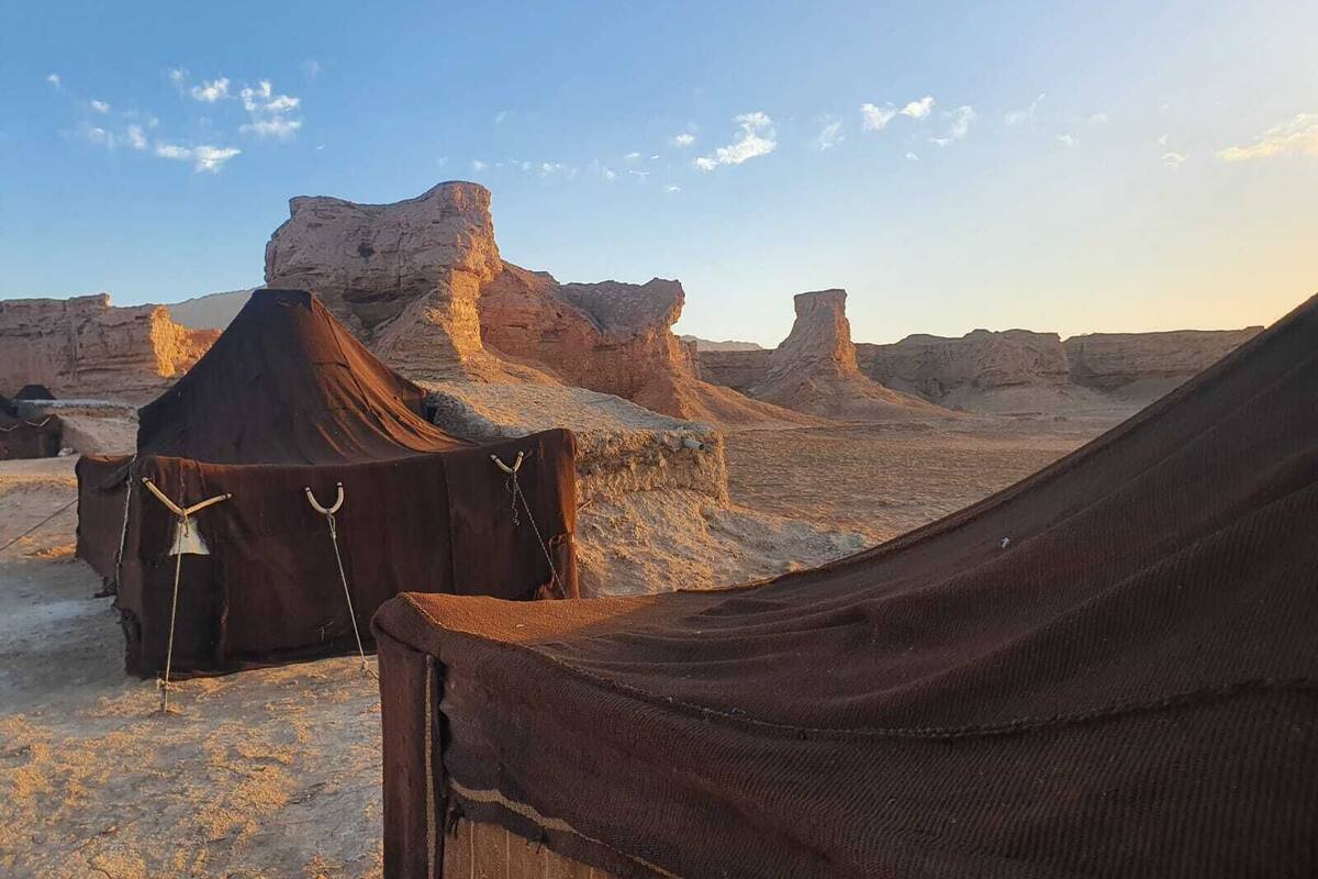 A desert landscape with tents and rocky formations.