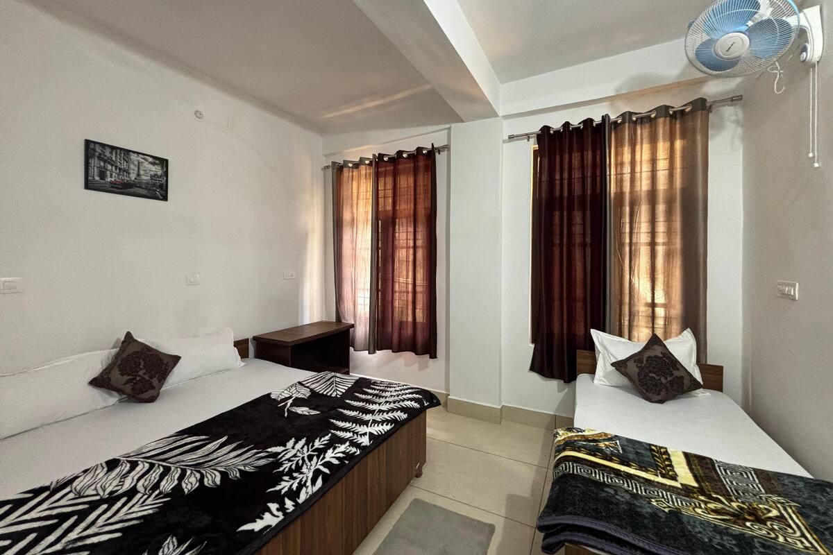 Een kamer met twee éénpersoonsbedden, een kleine tafel, een ventilator en een foto aan de muur.