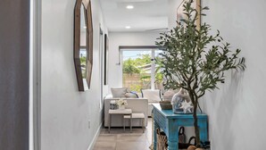 Un couloir avec un canapé blanc, une petite table et une console bleue agrémentée d’objets décoratifs.