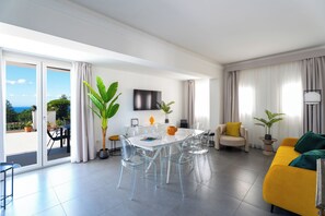 A modern living room with a dining area, large windows, and a view of the outdoors. - Domus Rubina (Sorrento)