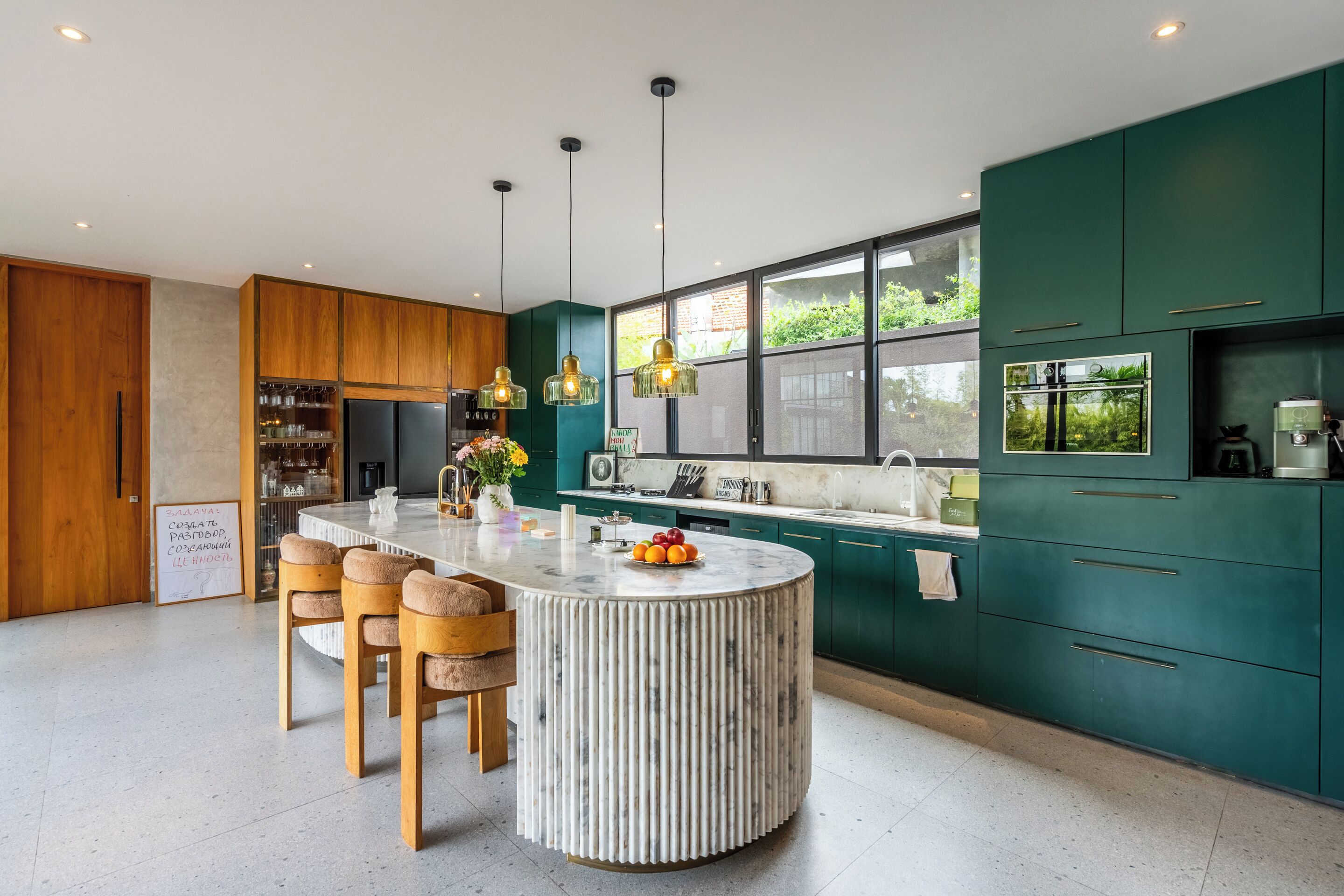 A modern kitchen with a central island, wooden chairs, and pendant lighting.