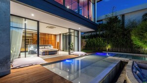A modern house with a glass-enclosed living area, a wooden deck, and an infinity pool. - Soul Moon Harmony - Harmony of Comfort and Nature (Kerobokan)