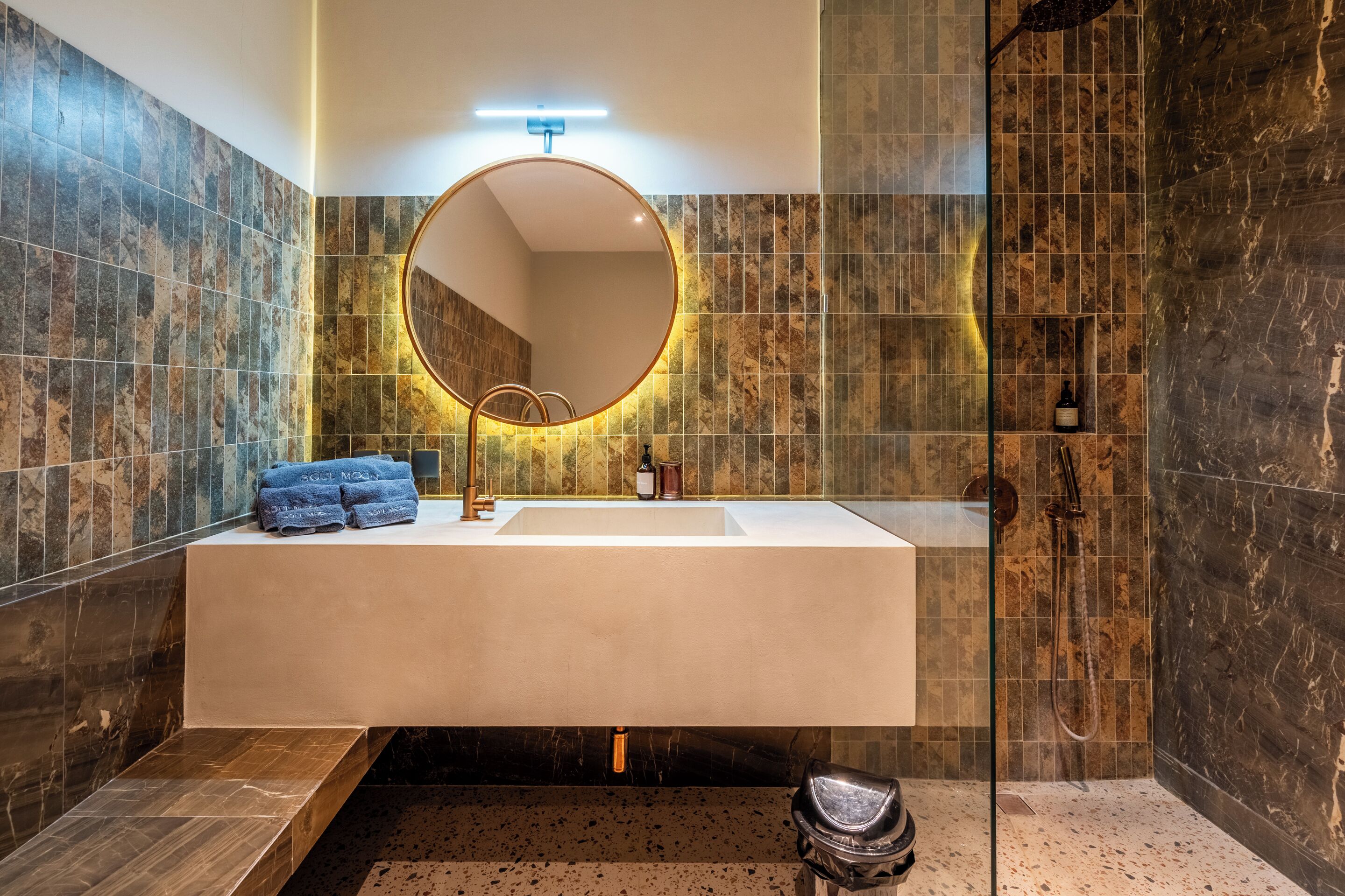 A modern bathroom with a large mirror, a sink, and a shower area.
