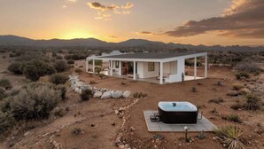 Une maison moderne dotée d’un patio et d’un jacuzzi, située dans un paysage désertique.