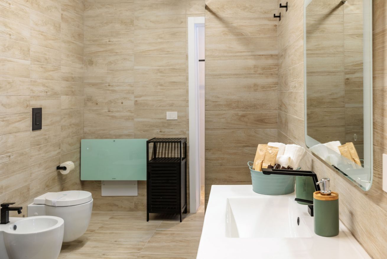 A modern bathroom with a toilet, bidet, sink, and a mirror.