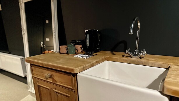 Une cuisine avec un évier blanc, des armoires en bois et un plan de travail.