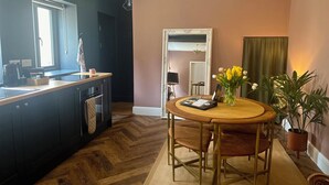 Une cuisine moderne avec un plan de travail en bois, une table à manger avec des chaises et un vase de fleurs.