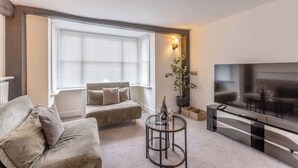 A living room with a sofa, a coffee table, a TV, and a window with blinds.