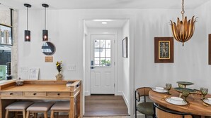 A modern kitchen with wooden countertops, pendant lights, and a dining area with a round table set for four.