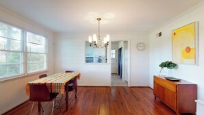 A dining area with a wooden table, chairs, a chandelier, and a view into the kitchen. - Charming 2-bedroom cottage on Daffin Park in beautiful Savannah with WiFi, AC (Savannah)