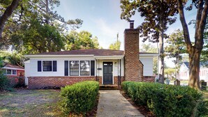 A single-story house with a brick chimney, a front door, and a small porch. - Charming 2-bedroom cottage on Daffin Park in beautiful Savannah with WiFi, AC (Savannah)