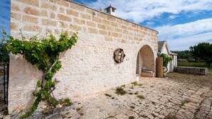 Un edificio de piedra con un muro de ladrillo, una pared cubierta de hiedra y un arco de entrada.