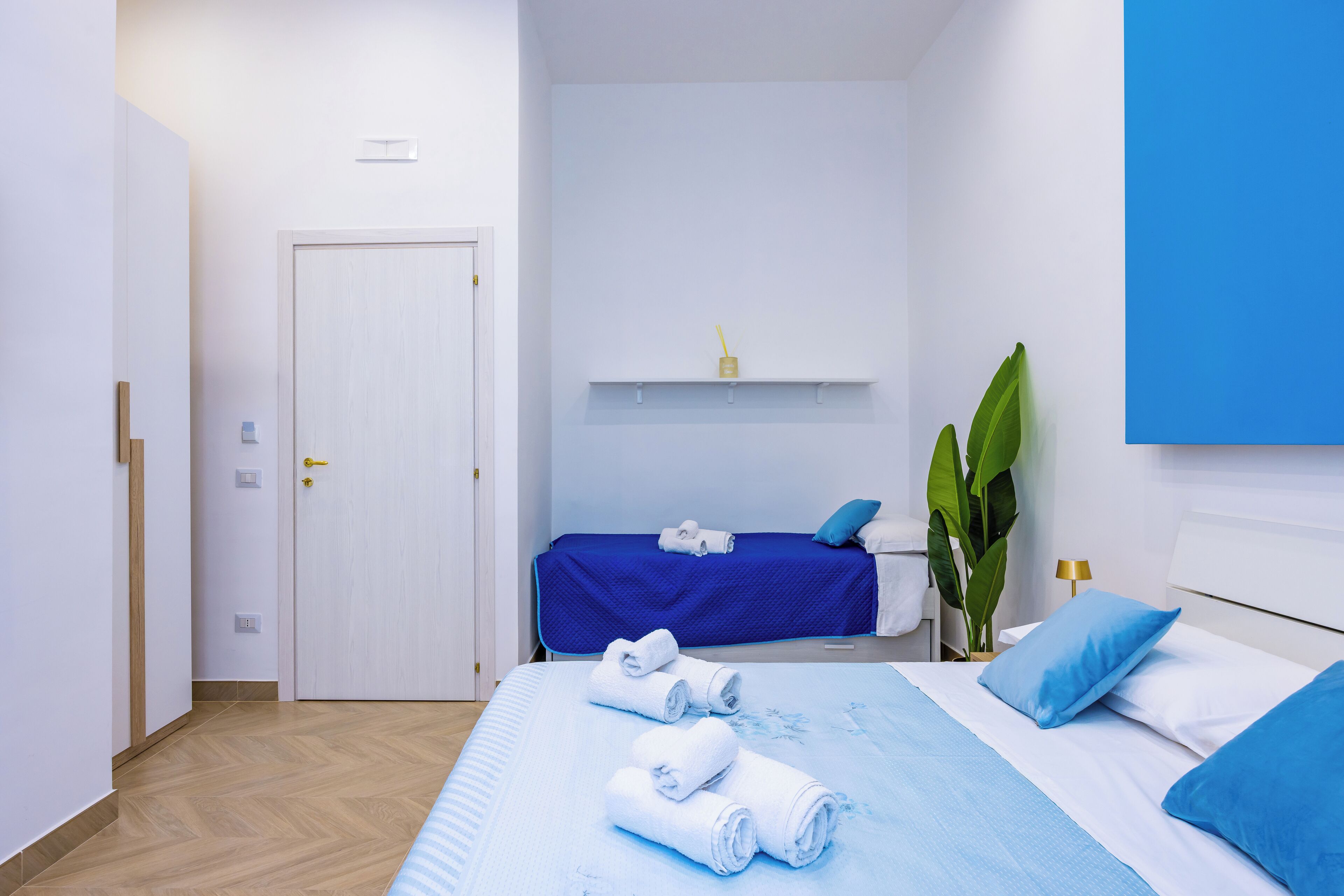 Une chambre d’hôtel avec un lit, un bureau et une chaise. Il y a une porte et une fenêtre.