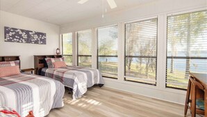 A bedroom with two beds, large windows, a ceiling fan, and a view of the outdoors. - Waterfront Lake Retreat • Private Dock & Fire Pit (Anacoco)