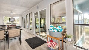 A spacious room with large windows, a television, and a seating area with chairs and a table. - Waterfront Lake Retreat • Private Dock & Fire Pit (Anacoco)