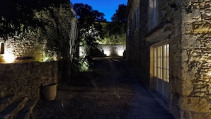 A narrow stone pathway leading to a stone building with a door, surrounded by greenery and a stone wall. - Le Mas Tillet (Goudargues)