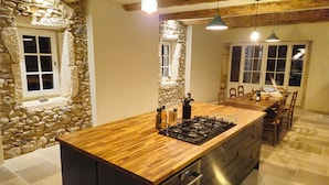 A kitchen with a wooden countertop, stone walls, and a large window. - Le Mas Tillet (Goudargues)