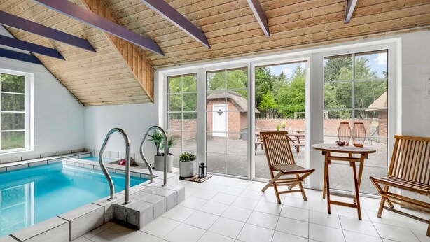 A modern indoor swimming pool with a wooden ceiling and large windows. - "Ulf" - 2km from the sea by Interhome (Ulfborg)