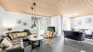 A modern living room with a black leather sofa, a black armchair, and a black leather couch. There is a small round table with a fruit bowl. The room has a wooden ceiling and a large window. - "Ulf" - 2km from the sea by Interhome (Ulfborg)