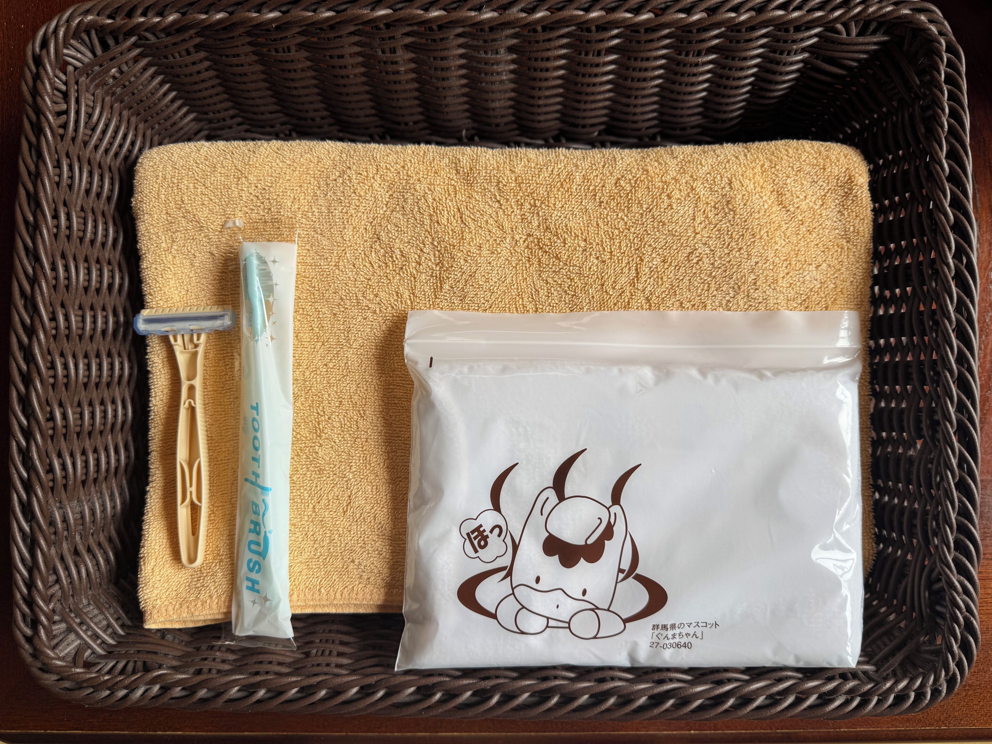A woven basket containing a toothbrush, a tube of toothpaste, and a pouch with a cow illustration.