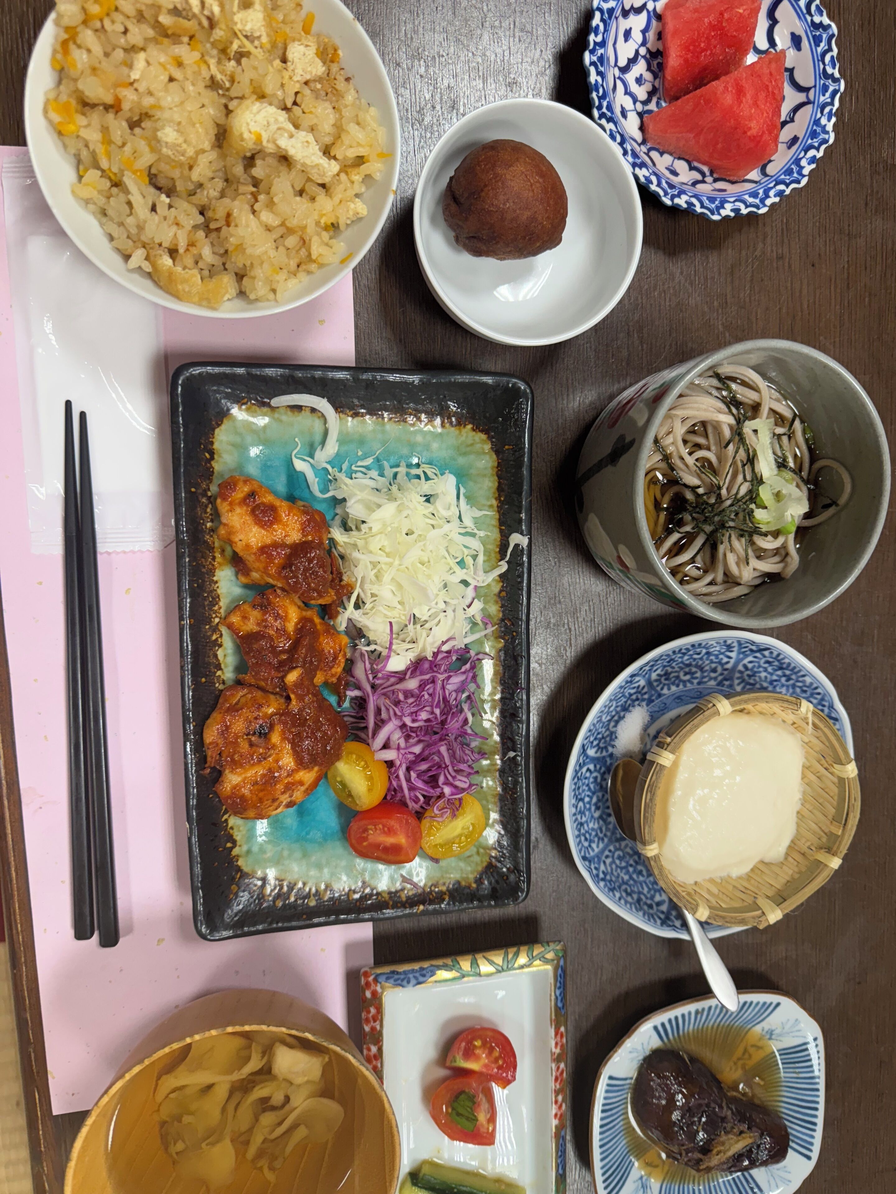 A table with various dishes including fried rice, a plate with meat, vegetables, and noodles.
