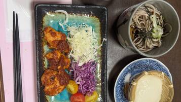 A table with various dishes including fried rice, a plate with meat, vegetables, and noodles.