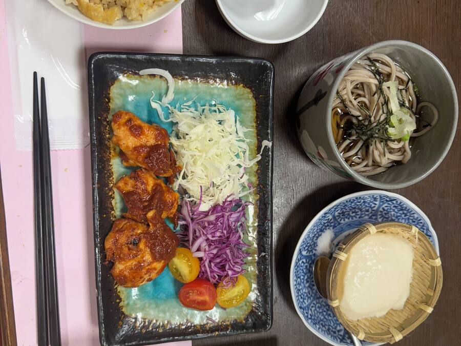 A table with various dishes including fried rice, a plate with meat, vegetables, and noodles.