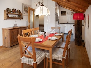 Zona pranzo con tavolo di legno apparecchiata per quattro, circondata da sedie di legno con cuscini a righe.