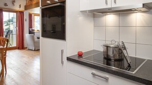 A modern kitchen with white cabinets, a built-in oven, and a stovetop.