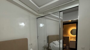 Ein modernes Hotelzimmer mit einem großen Bett, einer Glaswand und einem durch die Wand einsehbaren Badezimmer.