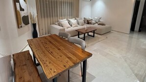 Ein modernes Wohnzimmer mit Esstisch aus Holz, einer Couch und einer Pendelleuchte.