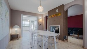 A modern dining area with a white table and chairs, a chandelier, and a fireplace. - Etna View Superior Flat with Terrace and Jacuzzi (Catania)