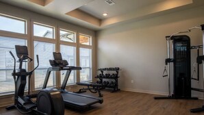 A home gym with a treadmill, elliptical, and weight rack. - Landing Apartments Waller (Waller)