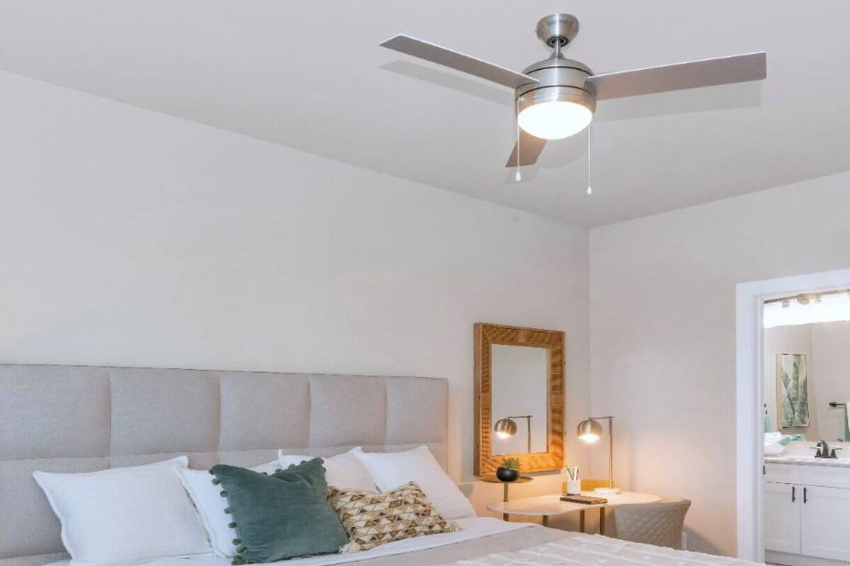 A neatly arranged bedroom with a bed, bedside table, and a ceiling fan.