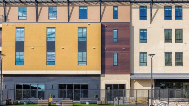 A modern building with a swimming pool in front. - Phoenix Goodyear Apartments by Landing (Goodyear)