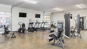 Ein Fitnessstudio mit Laufbändern, Crosstrainern und Kraftgeräten.