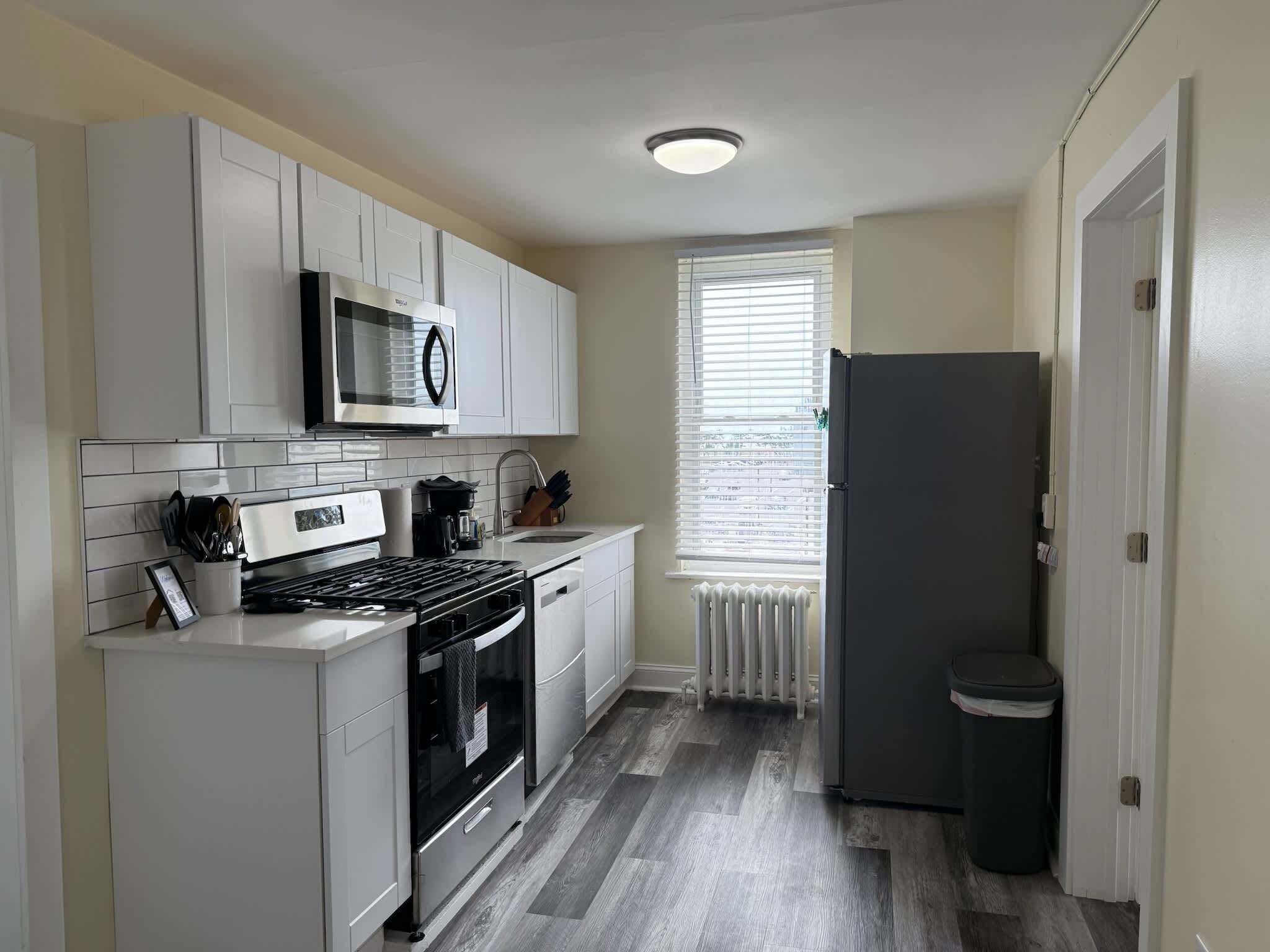 Una cocina moderna con armarios blancos, una estufa de acero inoxidable, un microondas y un refrigerador.