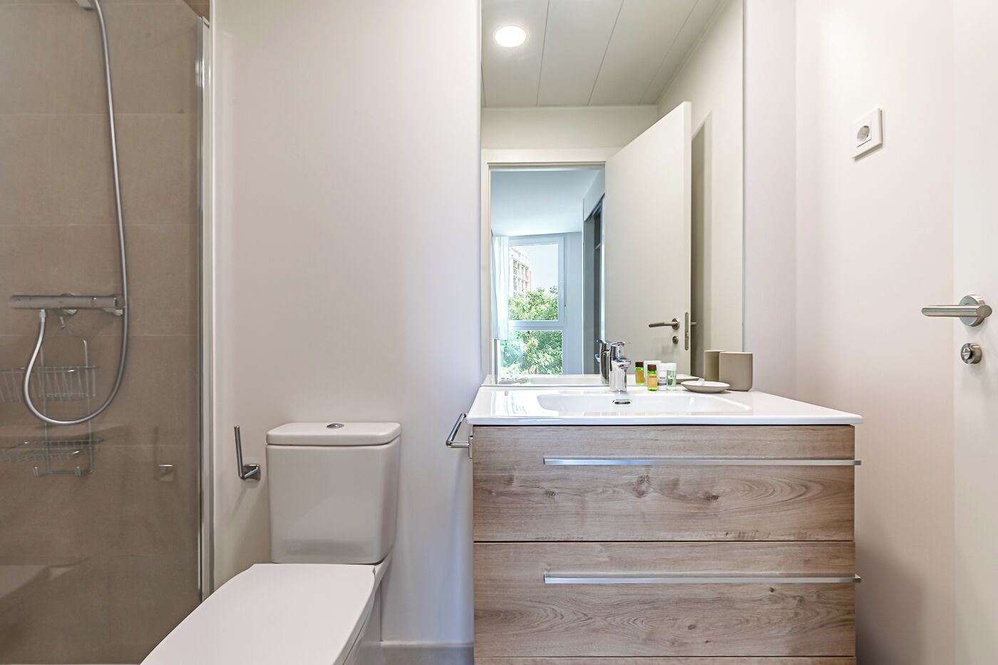Un baño moderno con ducha, inodoro y tocador con espejo.