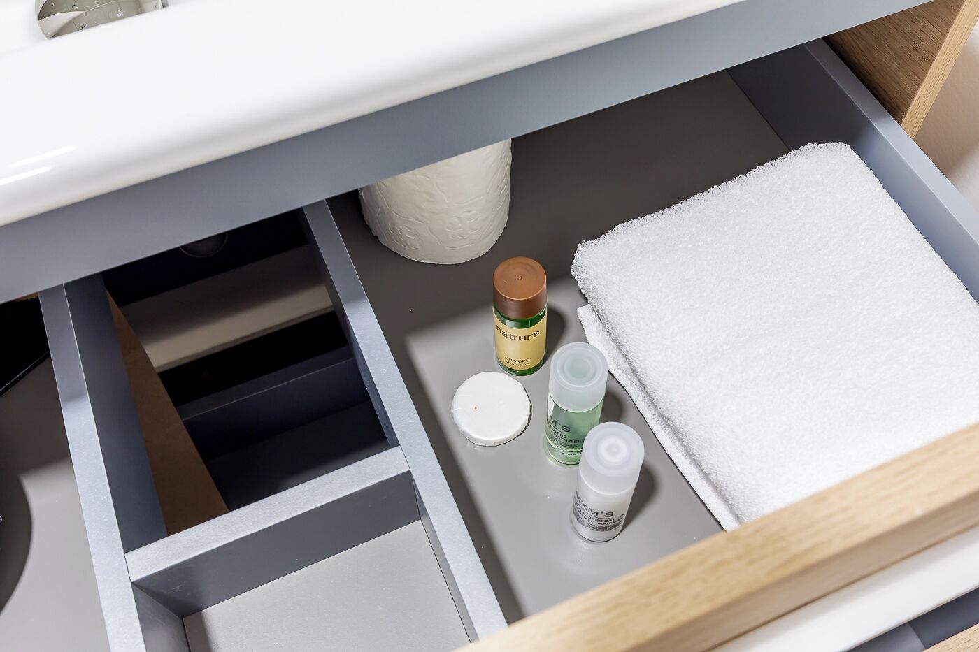 Un baño con una toalla blanca, una botella de champú y una botella de crema hidratante sobre el mostrador.