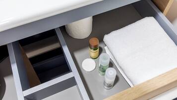 Un baño con una toalla blanca, una botella de champú y una botella de crema hidratante sobre el mostrador.