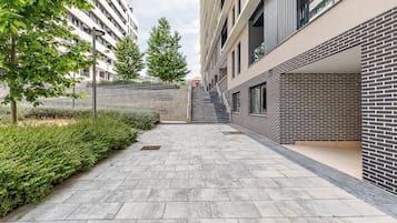 Ein moderner Stadtweg mit einer Ziegelwand an einer Seite und einem Gebäude mit großen Fenstern an der anderen.