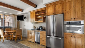 A modern kitchen with wooden cabinets, stainless steel appliances, and a dining area with a table and chairs.