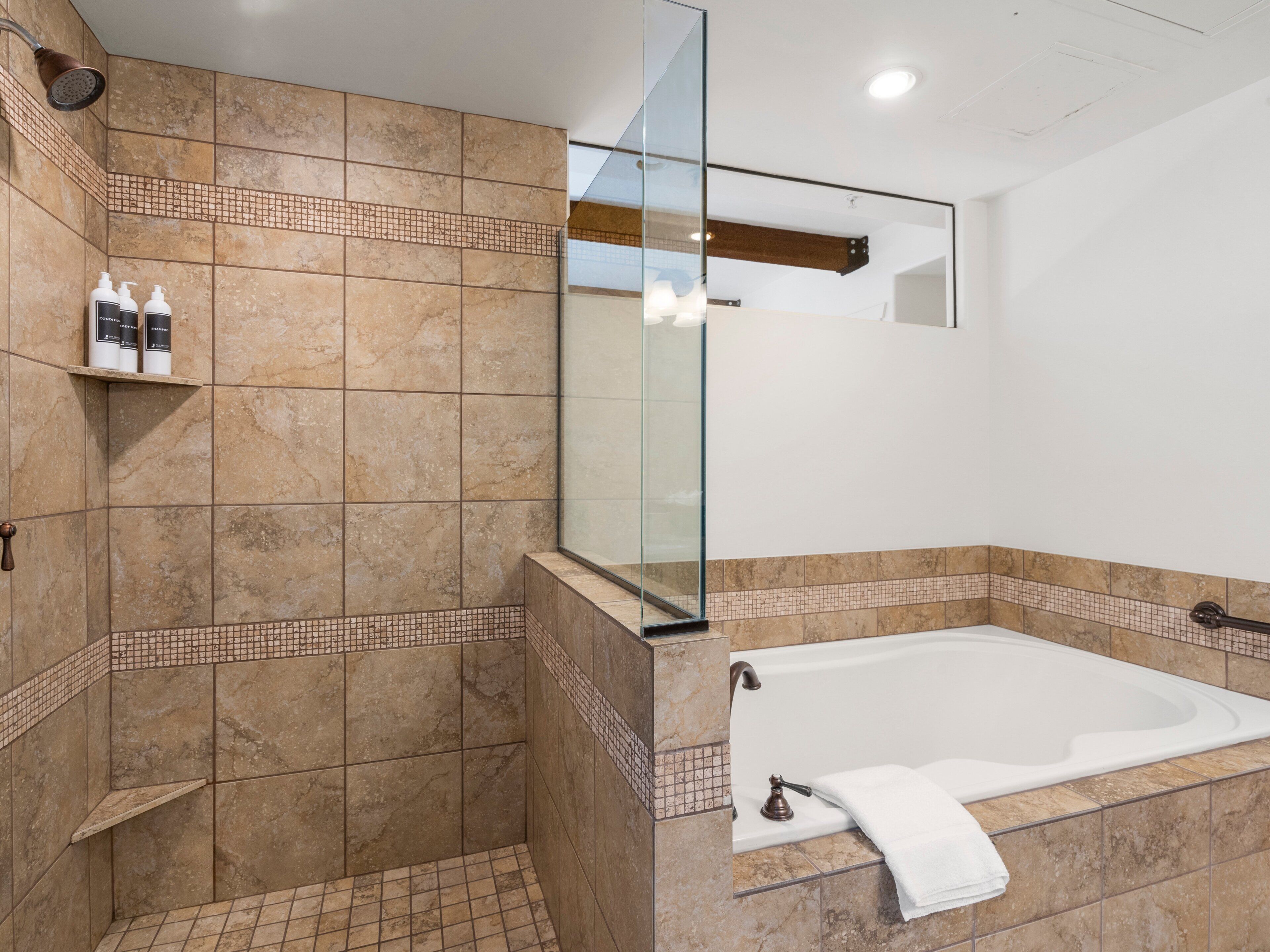 Un baño con ducha, bañera y cabina de ducha con paredes de vidrio.