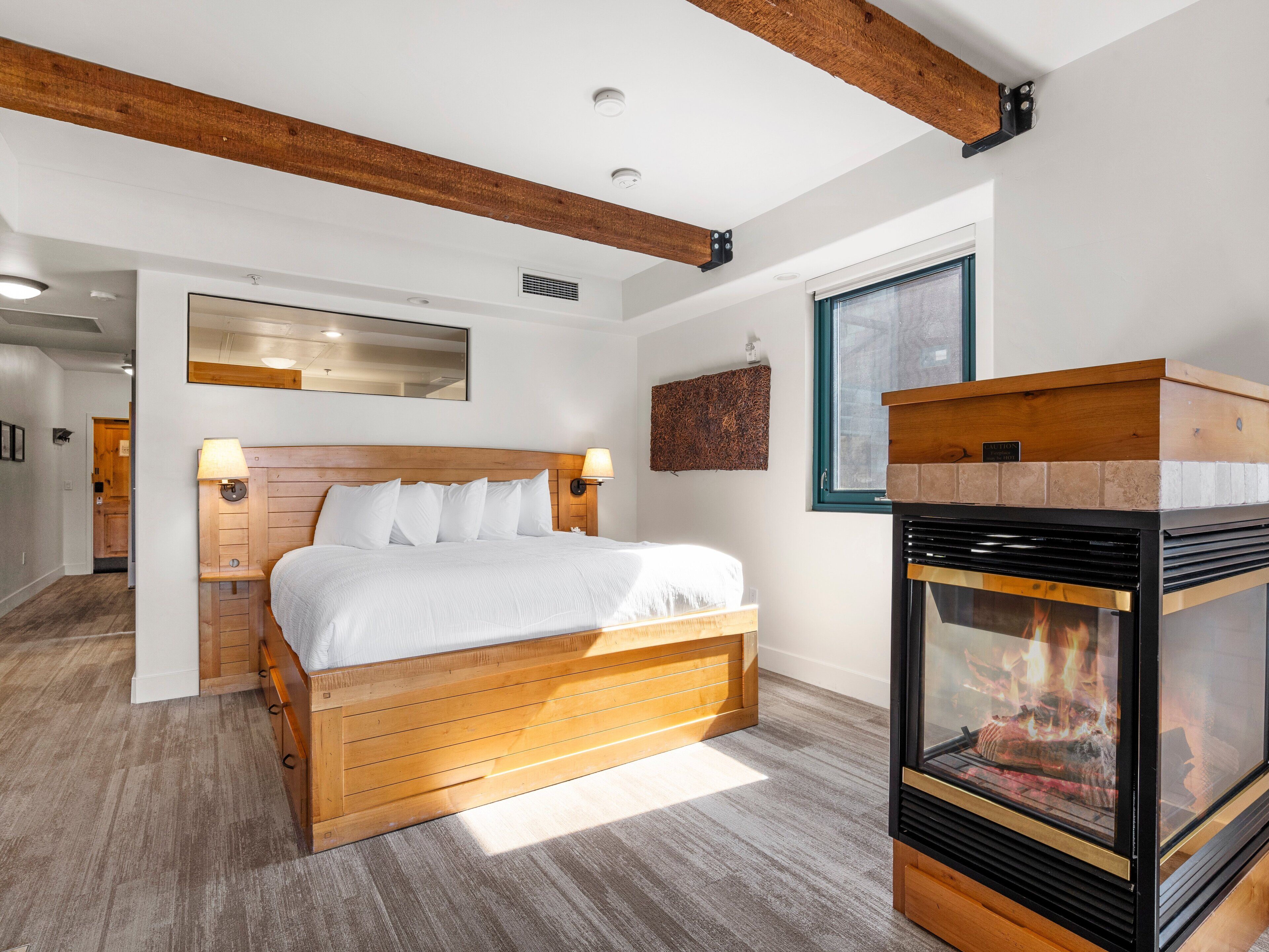 A bedroom with a wooden bed, a fireplace, and a large window.