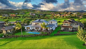Une grande maison à plusieurs étages, dotée d’une piscine, entourée de vastes pelouses verdoyantes et d’un terrain de golf.