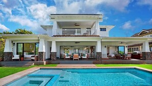 Une maison à deux étages dotée d’une piscine, d’un espace salon extérieur et d’un patio couvert.