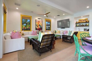 Una sala de estar con un sofá, sillones, una mesa de comedor y un televisor.